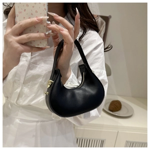 Detailed view of black crescent leather handbag with gold metal lock and smooth zip closure