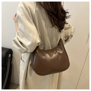 Detailed view of deep brown semi-circle shoulder bag with glossy leather and minimalist curves