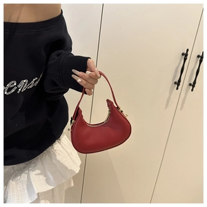 Close-up of red leather crescent handbag featuring elegant gold zipper and hardware