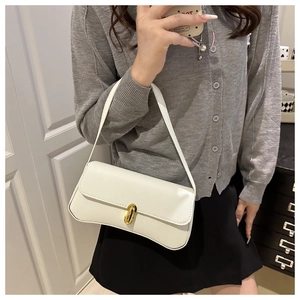 Detail of white lychee leather texture and golden oval swivel clasp on chic baguette bag