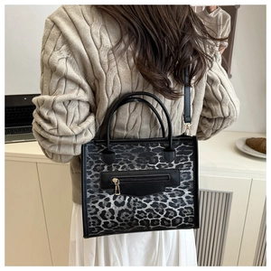 Detail of leopard print tote bag featuring black zipper pocket and golden hardware