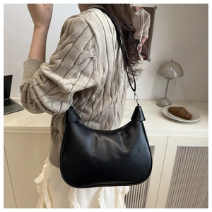 Side view of a black glossy leather saddle bag with slim strap and silver metal buckle