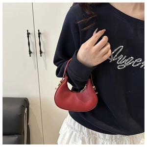 Detail of red mini crescent handbag featuring smooth texture and gold metal hardware