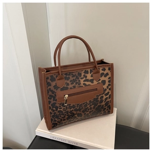 Detail of leopard print tote bag with brown handles and a gold zippered front pocket