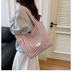 Detail shot of a large red and white striped canvas tote bag with a woven brand label