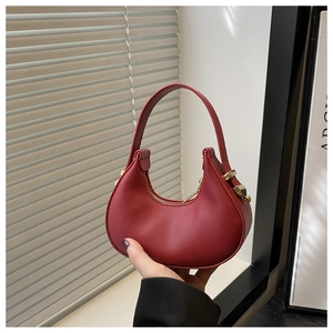 Detail of red crescent handbag with matte leather texture and gold metallic buckle