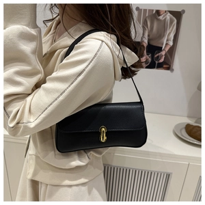 Detail of black lychee grain leather underarm bag with gold oval twist lock on shoulder