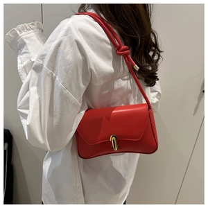 Détail du sac rouge en cuir avec bandoulière à nœud et fermoir doré rotatif en métal