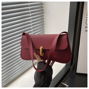 Close-up of wine red baguette bag with lychee grain leather and golden U-shaped clasp
