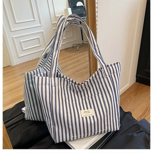 Detail view of large blue and white striped canvas tote bag with textured fabric straps