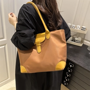 Large brown nylon tote bag with yellow leather trim shown on a model in a modern room