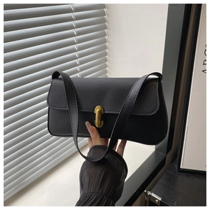 Close-up of black lychee grain leather underarm bag with gold oval twist lock closure