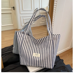 Close-up of blue and white striped canvas tote bag showing double handles and front pocket