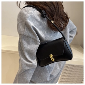 Détail du sac à main en cuir noir avec fermoir doré et bandoulière à nœuds élégante