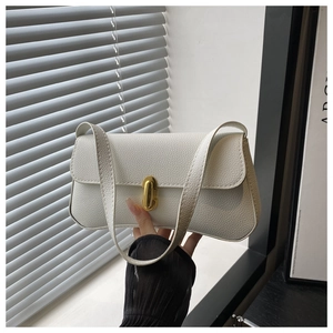 Detail of white minimalist baguette bag featuring golden turn-lock and lychee texture