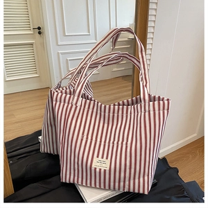 Detailed view of red and white striped canvas tote bag with front pocket and fabric label