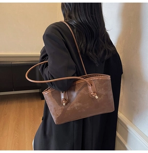 Detail showing vintage brown matte leather texture and knotted metal buckles on shoulder bag