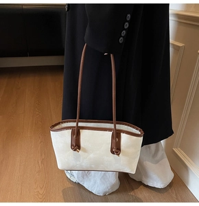 Detail of cream minimalist tote bag with dark brown knotted leather handles and logo