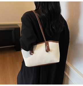 Detail view of stylish white leather shoulder bag with brown straps on a model back