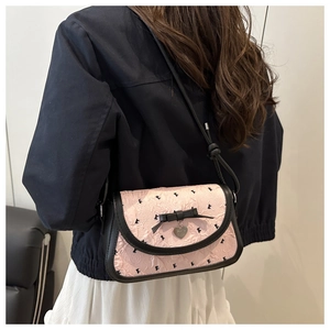 Detail showing pink pleated crossbody bag with black bow embroidery and heart charm