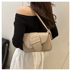 Side view of beige minimalist shoulder bag with gold buckle on a stylish model