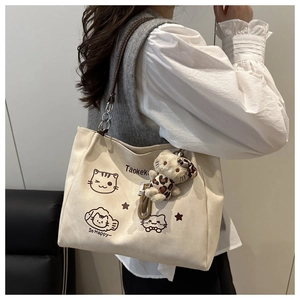 Detail view of canvas tote bag featuring cartoon cat print and plush leopard charm