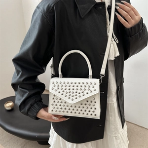 White mini crossbody bag with silver studs and top handle shown on a model body