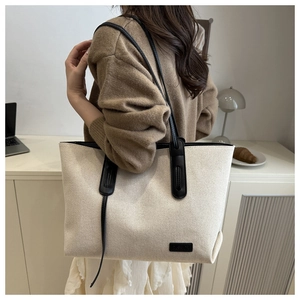 Detailed texture of off-white canvas tote bag with black leather strap and fashion label