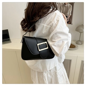 Detail of minimalist black leather crossbody bag with iconic gold square metal buckle