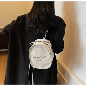 Rear view of a white mini round backpack with Trick OR Traet print on a black coat