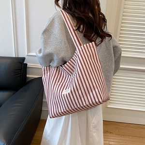 Red and white vertical striped canvas tote bag with wide shoulder strap on model