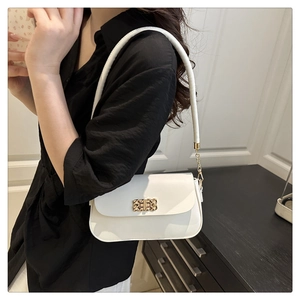 Détail du sac à bandoulière blanc avec fermoir en métal tissé doré et bandoulière chaîne