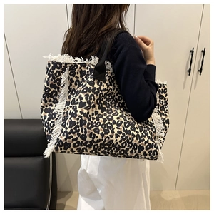 Detailed view of leopard print tote bag with white faux fur fringe and black strap