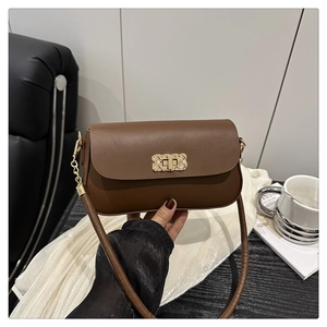 Détail d'un sac à bandoulière en cuir marron avec un fermoir doré à texture tressée
