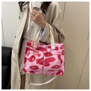 Dettaglio della borsa tote in tela rosa con tasche frontali e manici beige sul modello