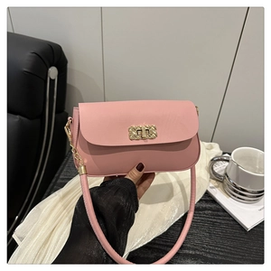 Gros plan d'un sac sous le bras en cuir rose avec un fermoir en métal doré tressé