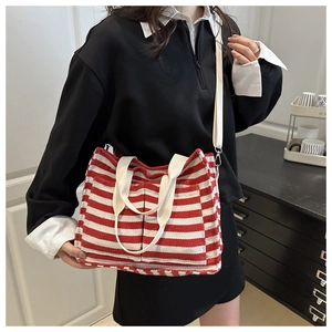 Detail of red and white striped canvas tote bag with adjustable strap worn by model