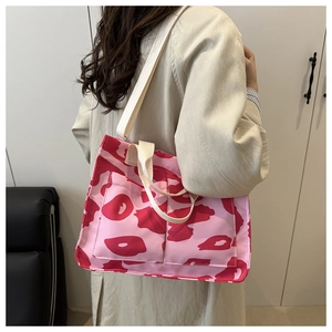 Dettaglio laterale di borsa tote con motivi astratti rosa e tracolla bianca larga
