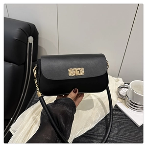 Détail du sac à bandoulière carré noir avec boucle décorative en métal doré tissé