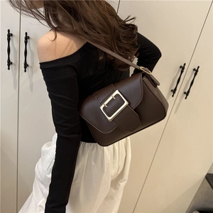 Brown leather crossbody bag with a large gold buckle shown on a model for casual style