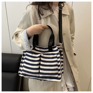 Blue and white striped canvas tote bag detail with front pockets and black straps