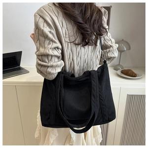 Detail einer großen schwarzen Cord-Stofftasche an einem Modell in einem Büro-Ambiente