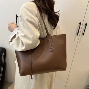 Brown leather tote bag with FASHION logo shown on model wearing a beige trench coat