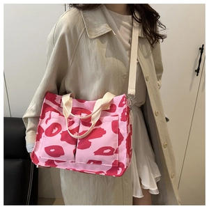 Dettaglio della borsa tote in tela rosa con motivi camo rossi e ampie tasche frontali