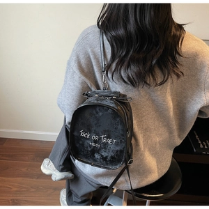 Close-up of black mini backpack featuring white Trick or Treat print and silver zippers