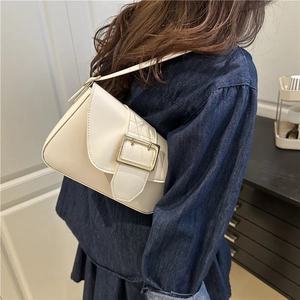 Minimalist beige crossbody bag with gold square buckle shown on a model's shoulder