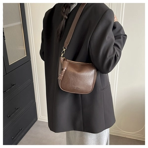 Détail du sac bandoulière en cuir grainé marron foncé avec gaufrage FASHION et frange