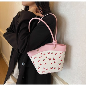 Detail of pink and white cherry print bucket bag with golden metal eyelets and PU leather