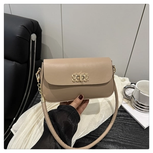 Détail du fermoir métallique tissé et de la bandoulière en chaîne dorée du sac beige