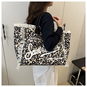Detail of leopard print tote bag featuring white fringe edges and bold black handles